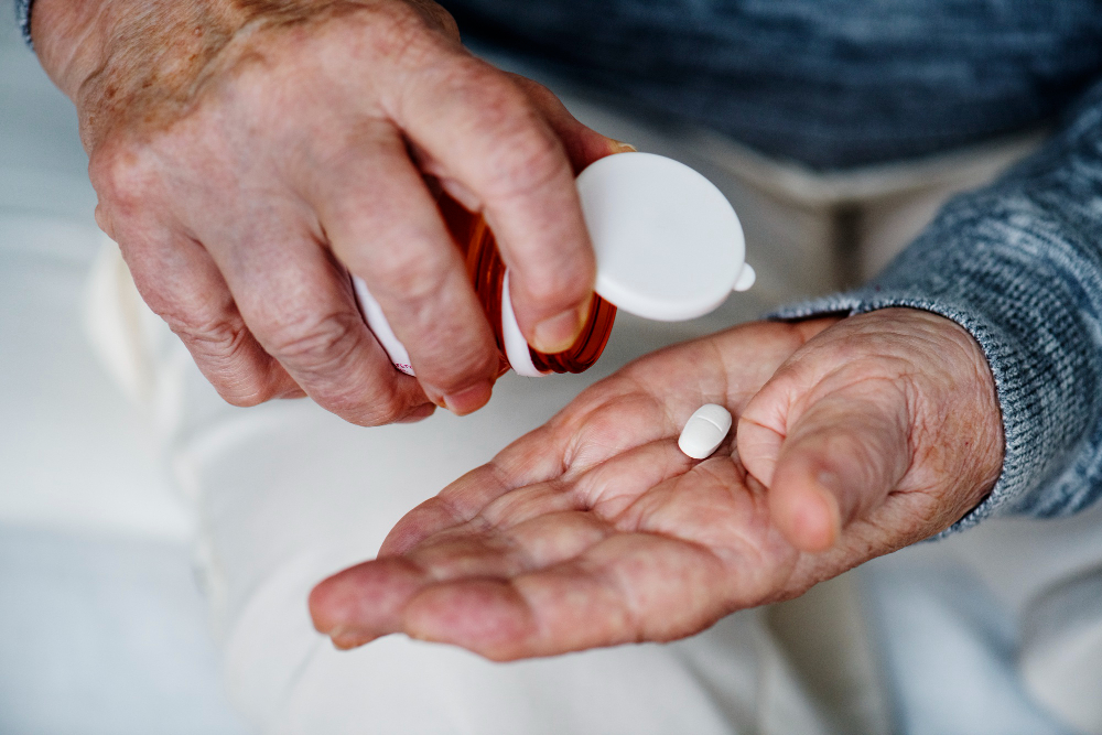 Pain Management for the Elderly – an older adult holding medication tablets in their hand, representing the importance of responsible dosing and avoiding overmedication.